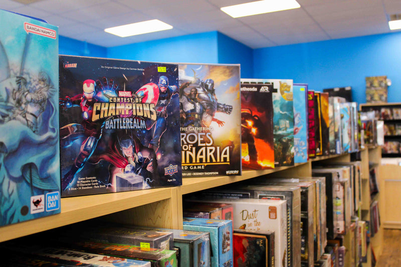 Shelves with board games on display. Prominently, the contest of champions battlerealm board game.