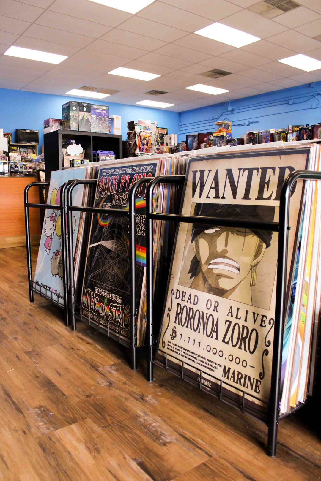 Posters on rack display of one piece wanted poster of roronoa zoro, pink floyd poster, and hello kitty x pusheen poster. Find posters of anime, music, movies, video games, and more at planet comics.