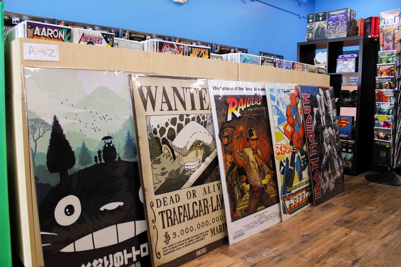 Posters on display. Buy one get one fifty percent off posters of totoro from studio ghibli, a wanted one piece poster, an indiana jones poster, a japanese transformers poster, and an iron maiden poster.