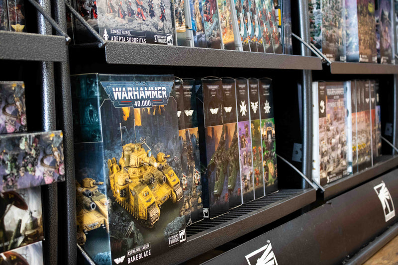 Shelf display of warhammer 40k boxes of different types of miniatures. Featured box is of astra militarium baneblade.